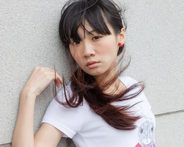 Asian girl against wall — Stock Photo, Image