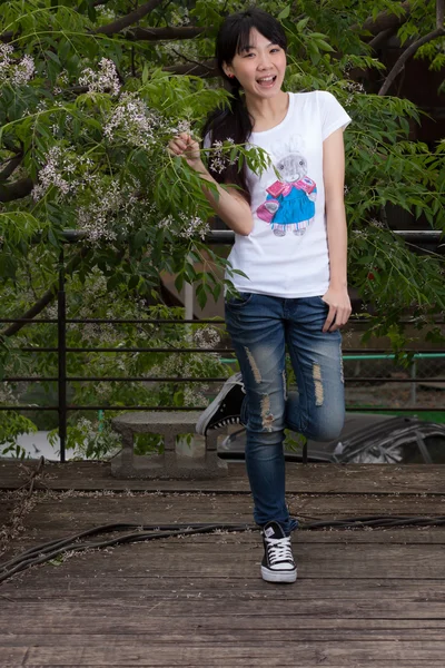 Menina asiática de pé entre folhas — Fotografia de Stock