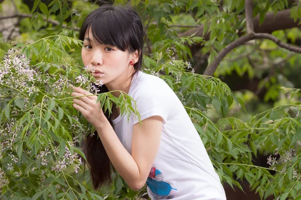 Asian girl standing amongst leaves — Stock Photo, Image