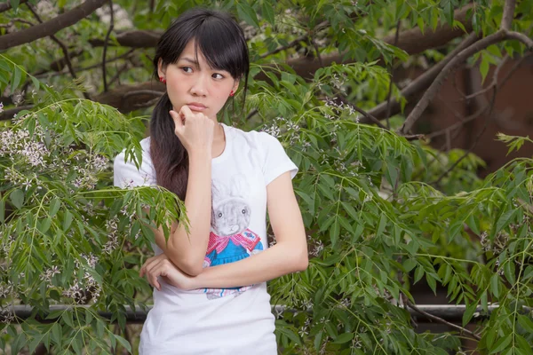 Asiatisches Mädchen steht zwischen Blättern — Stockfoto