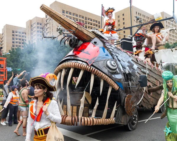 Gekostumeerde feestgangers maart met drijvers in de jaarlijkse droom parade o — Stockfoto