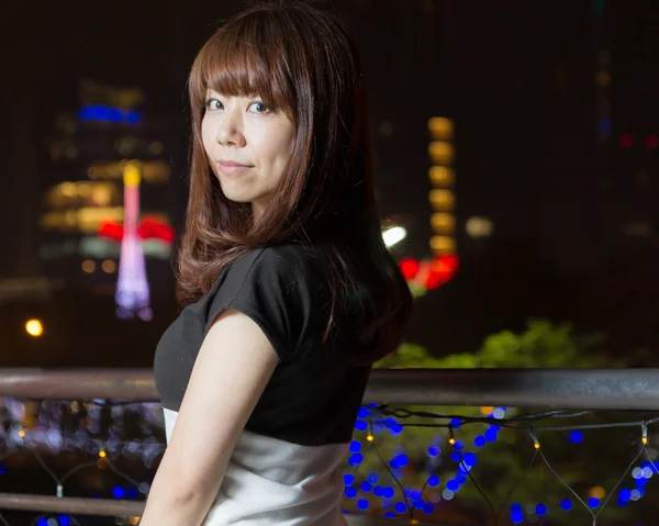 Pretty Asian woman with city light behind her — Stock Photo, Image