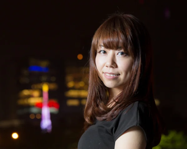 Pretty Asian woman with city light behind her — Stock Photo, Image