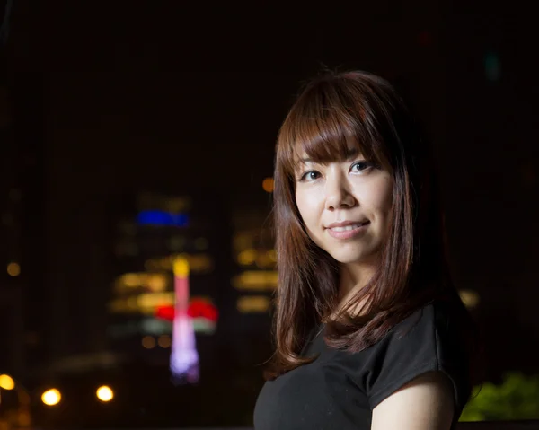 Mujer asiática bonita con luz de ciudad detrás de ella — Foto de Stock