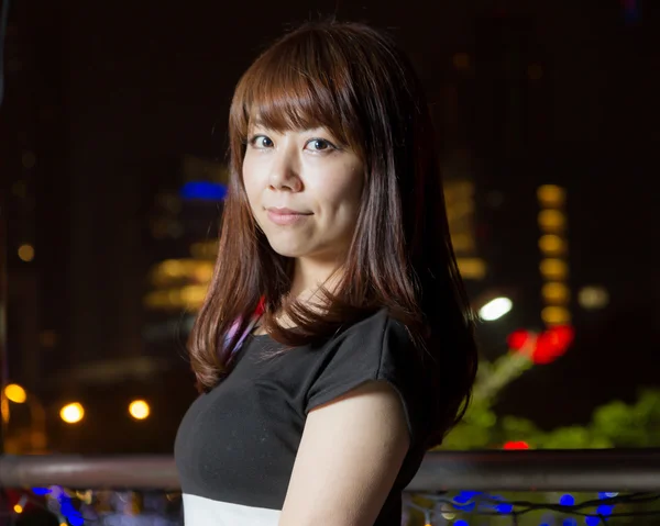 Pretty Asian woman with city light behind her — Stock Photo, Image