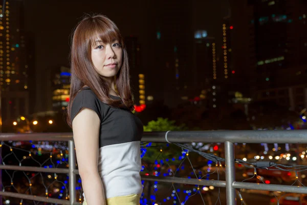 Pretty Asian woman with city light behind her — Stock Photo, Image