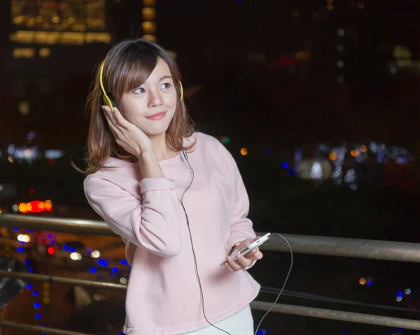 Hermosa mujer asiática usando auriculares y sosteniendo el teléfono celular — Foto de Stock