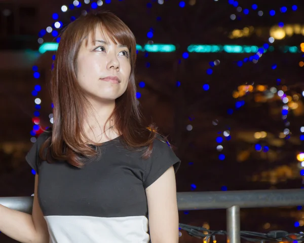 Pretty Asian woman in front of city lights — Stock Photo, Image