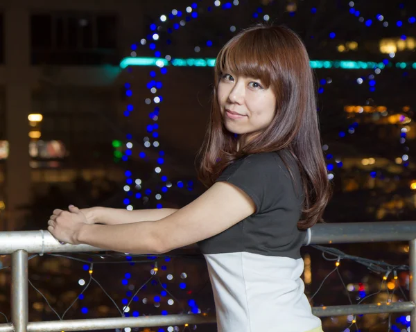 도시의 불빛 앞에서 웃는 아시아 여자 — 스톡 사진