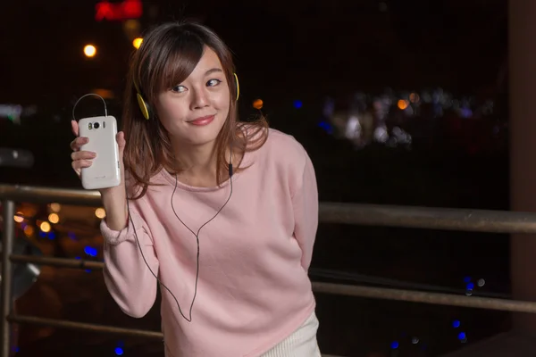 Expresiva mujer asiática con teléfono inteligente y auriculares amarillos — Foto de Stock