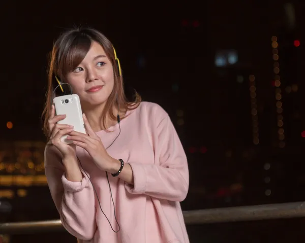 Beautiful Asian woman with smart phone and yellow headphones — Stock Photo, Image