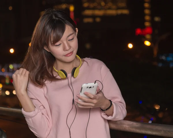 Beautiful Asian woman with smart phone and yellow headphones — Stock Photo, Image