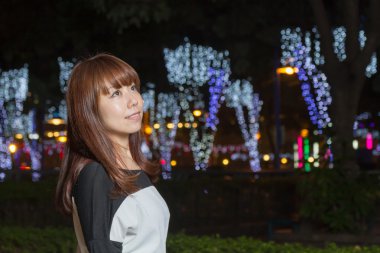 Asyalı kadın bir park ışıkları onun arkasında duran