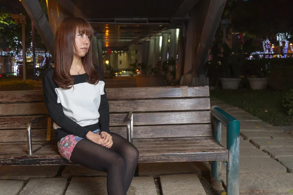 Грустная азиатка на скамейке в парке — стоковое фото