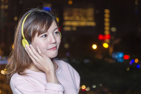 Beautiful young Asian woman wearing yellow headphones — Stock Photo, Image