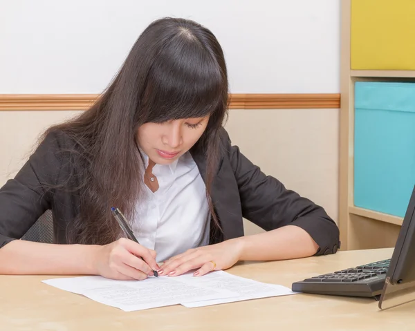 Mulher asiática escrevendo na mesa de escritório — Fotografia de Stock