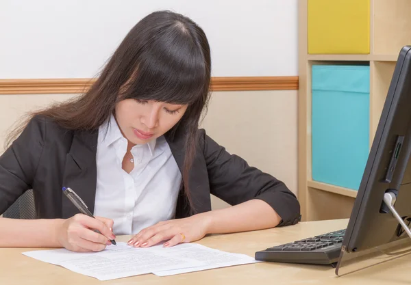 Chinese  woman at desk writing — Stock Photo, Image