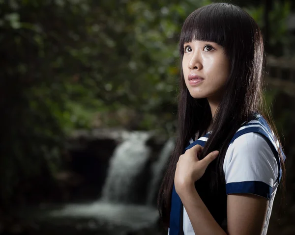 Asian schoolgirl standing in front of waterfall — Stock Photo, Image