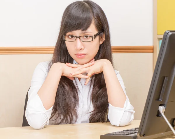 Kinesisk kvinde ved skrivebordet ser alvorlig - Stock-foto