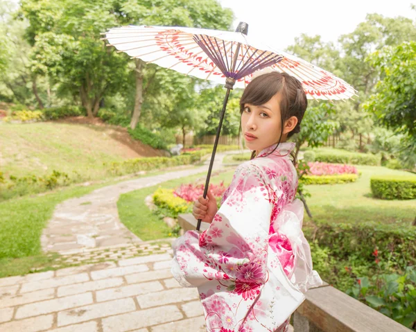Bir yukata giymiş ve Japonca bir şemsiye tutan Asyalı kadın — Stok fotoğraf