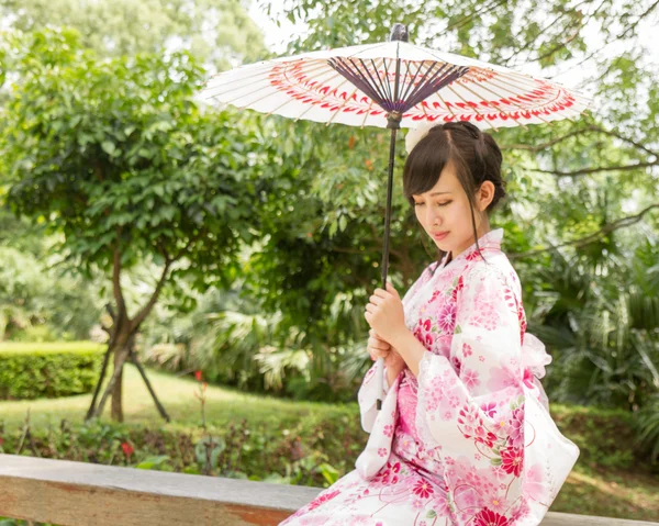 Asyalı Japon tarzında bir şemsiye ile yukata giymiş 