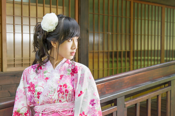Asian woman wearing a yukata in front of Japanese style windows