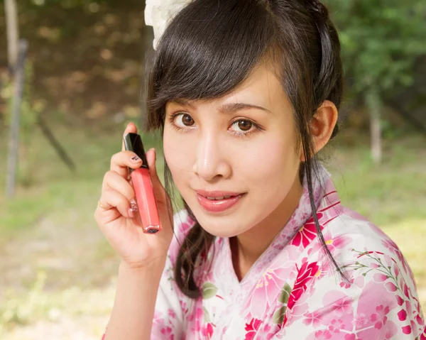 Mujer asiática usando un kimono sosteniendo el brillo de labios — Foto de Stock