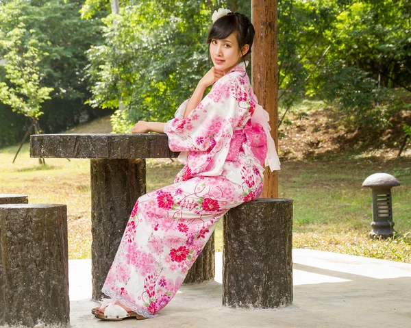 Azjatycki dama sobie siedzi w ogród japoński kimono — Zdjęcie stockowe