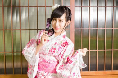 Asyalı Japon ahşap pencerelerin önünde bir kimono giymiş