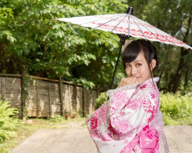 Asyalı Japon bahçesinde oturan bir kimono giymiş