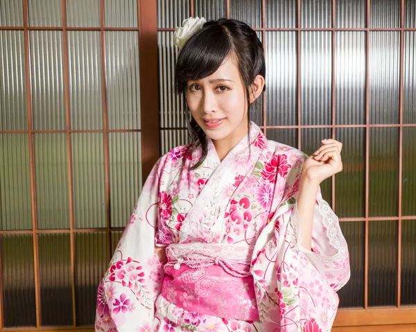 Aziatische vrouw die een kimono draagt voor Japanse houten ramen — Stockfoto