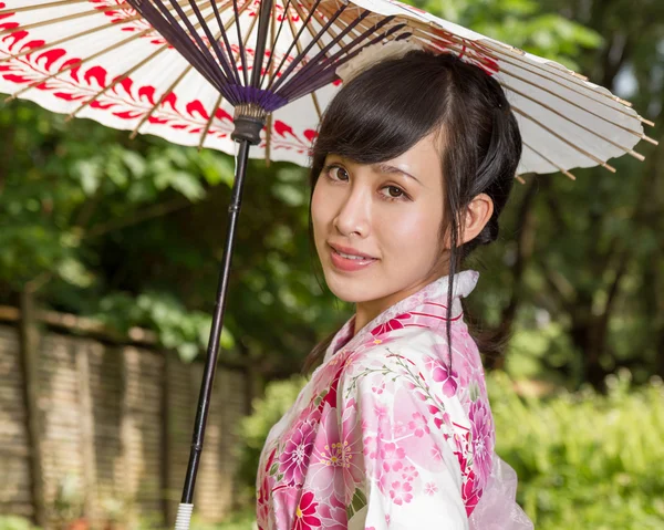 Asijské žena nosí kimono sedí v japonské zahradě — Stock fotografie