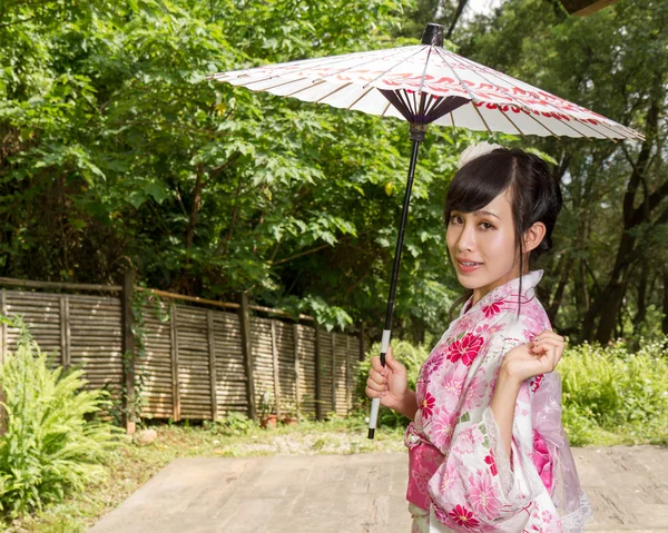 Asiatisk kvinna bära en kimono som sitter i japanska trädgården — Stockfoto