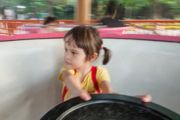 Young girl on spinning teacup, intentional motion blur — Stock Photo, Image