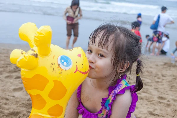 Young girl playing at beach kissing a toy giraffe — Stock Photo, Image
