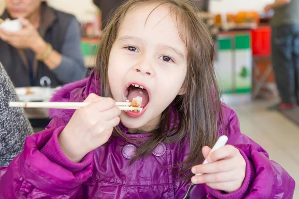 Ung blandade asiatiska kaukasiska flicka äter med pinnar — Stockfoto