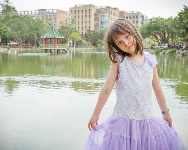 Menina no vestido de pé na frente de um lago — Fotografia de Stock