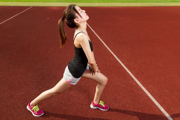 Chinoise athelete étirement des jambes sur le terrain de sport, réchauffement — Photo