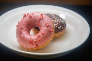 Beyaz tabakta çilekli ve çikolatalı çörekler.