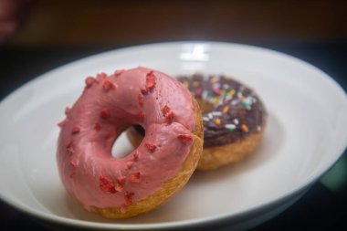 Beyaz tabakta çilekli ve çikolatalı çörekler.