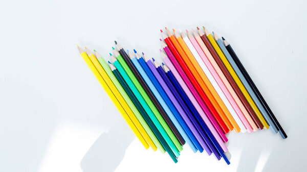 Colored pencil crayons in a row on white background