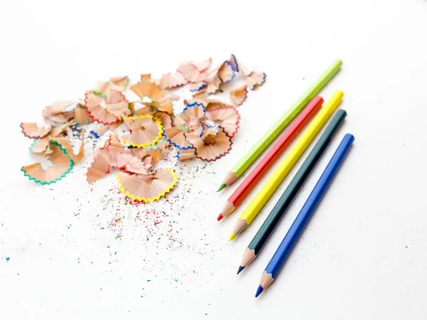 Colored pencil crayons in a row with shavings on white background