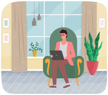 Evdeki koltukta dizüstü bilgisayarlı bir adam oturuyor. Uzaktan çalışma, çevrimiçi serbest çalışma, internet sörfü.