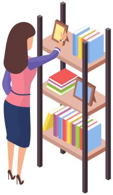 Rafın yanında duran, elinde fotoğraf çerçeveleri ve kitaplarla kitap arayan bir kadın.