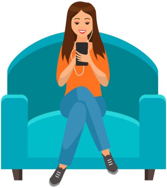 Kanepede oturan, müzik dinleyen ve akıllı telefondan sosyal medyayı karıştıran kulaklıklı kadın.