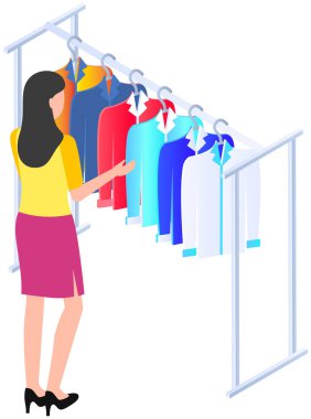 Woman choosing clothes, varicoloured shirts hanging on hangers, elements of wardrobe in store. Female shopper stylist standing at hangers and looking at outfit. Fashion clothes store, shopping concept