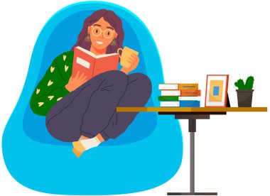 Kitap okuyan genç bir kadın, modern koltukta yastıkların üzerinde oturuyor. Boş zaman ve eğitim. Edebiyatla rahatlamak. Kız evde dinleniyor ve kahve içiyor. Öğrenci ders kitabı okuyor. Elinde bardak tutuyor.