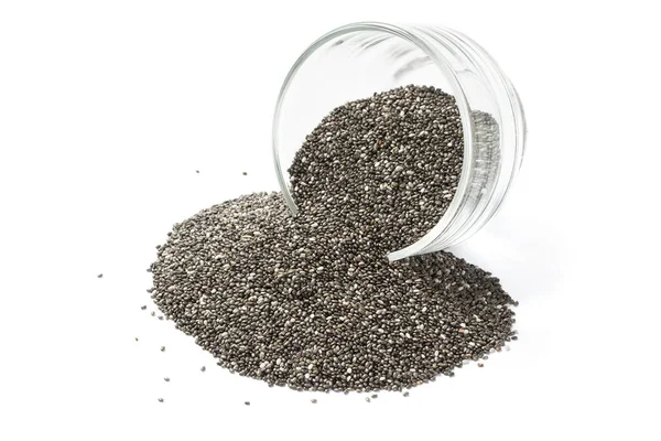 Beyaz arka planda cam kaseli Chia tohumları. Cam kaseye saçılmış Chia tohumları..