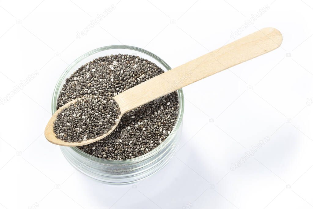 Chia seeds in wooden spoon with glass bowl on white background 