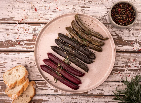 Grilled, roasted vegan, vegetarian sausages, top view. Rustic composition with bread, spices and fresh herbs. Serving proposal, on a plate, on white vintage boards. Plant based, meat free products.